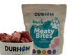 Durham Duck Meaty Bites with vegetables in a turquoise-labelled bag beside a bowl of frozen bites.
